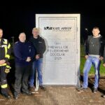 Dennis Schneider und Wehrführer Peter Haß nehmen die Übungstür von Azubi Björn Mehlert, Alexander Fülster und Benjamin Kassel von der Fa. Wrede entgegen
